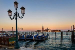 Sunset in Venice pointed at the sea. An old gas lamp is in the foreground